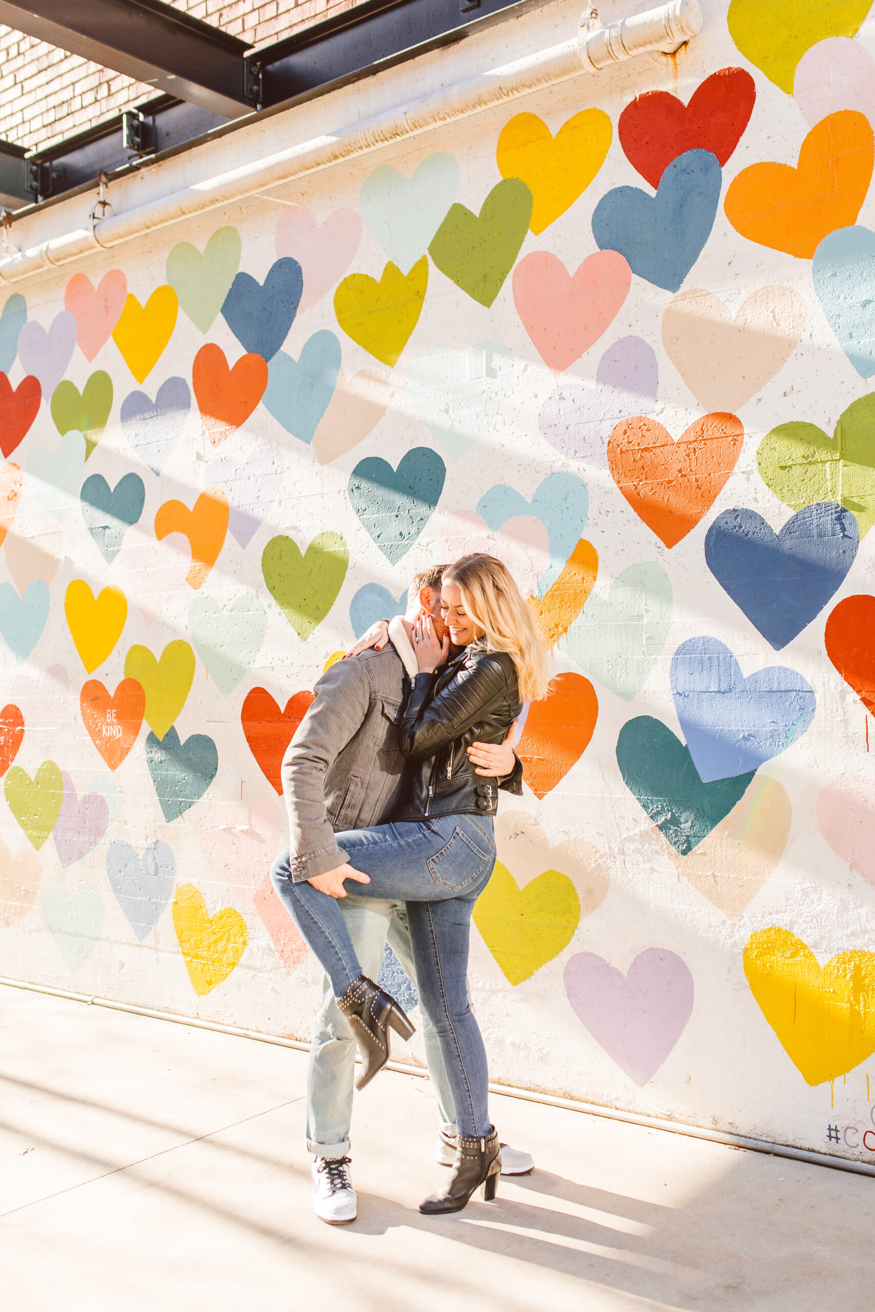 Couple posing by Confetti Hearts mural by Evelyn Henson on West Worthington Ave 