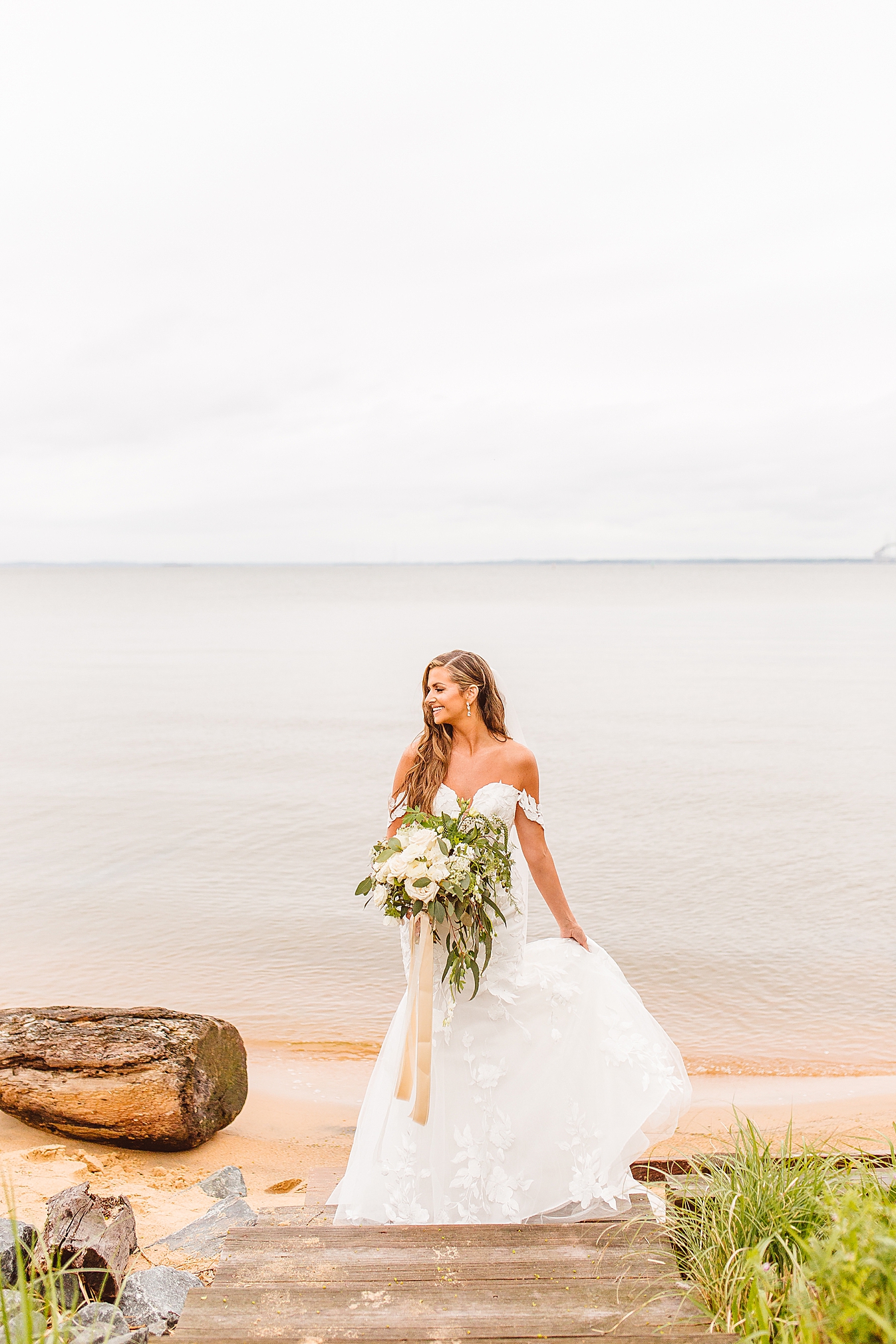 bride standing on beach holding bouquet at Chesapeake Bay Beach Club | Brooke Michelle Photo