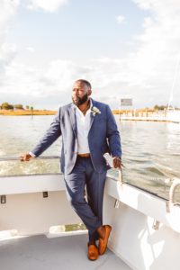 Groom standing on back of boat heading to ceremony at Wylder Hotel Tilghman Island | Brooke Michelle Photography