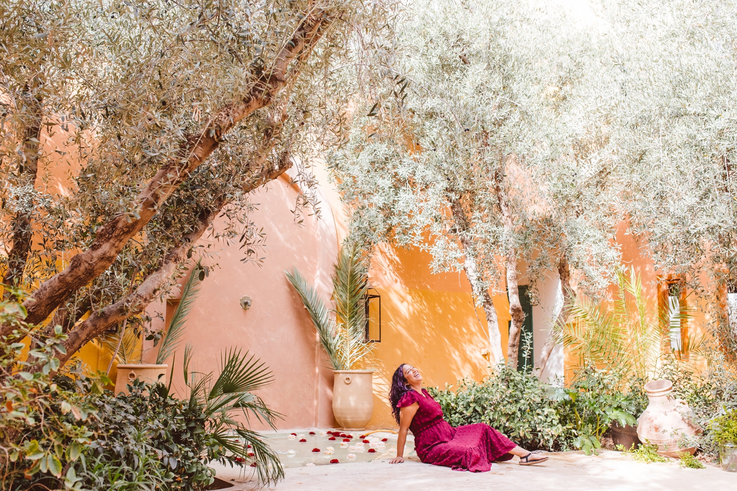 Woman sitting in front of pink and orange building in Morocco | Brooke Michelle Photography