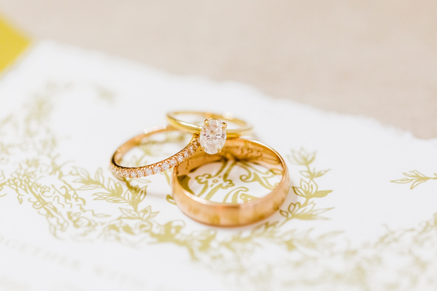Bride and groom's gold wedding rings set on top of wedding invitation | Brooke Michelle Photo