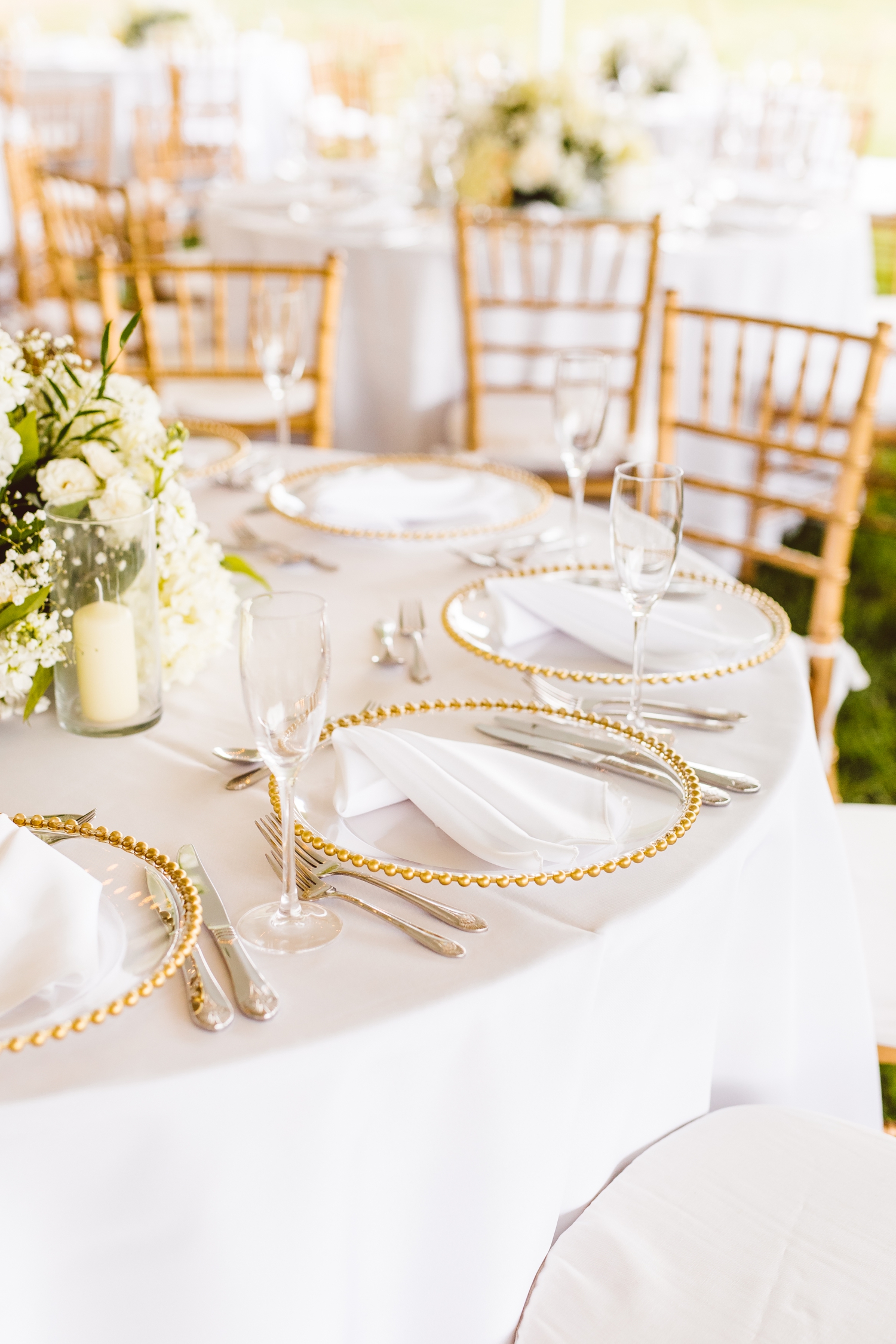 Gold chargers with gold silverware and white floral arrangements at Ladew Topiary Gardens wedding | Brooke Michelle Photo