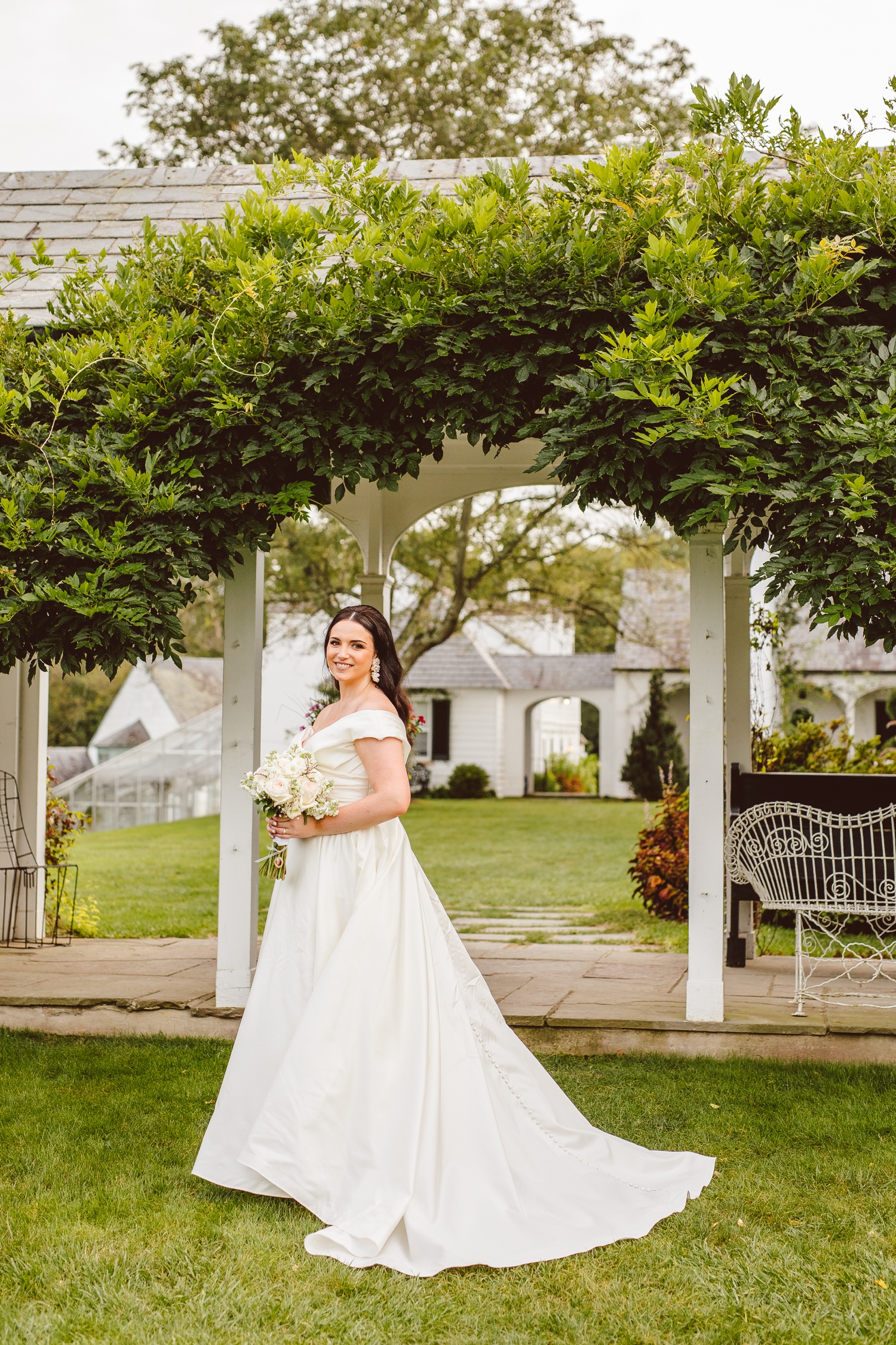 Bride standing under arch of greenery in Ladew Topiary Gardens | Brooke Michelle Photo