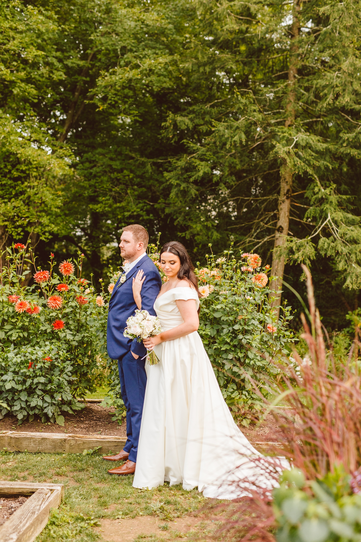 Bride and groom standing in front of flowers in Ladew Topiary Gardens | Brooke Michelle Photo