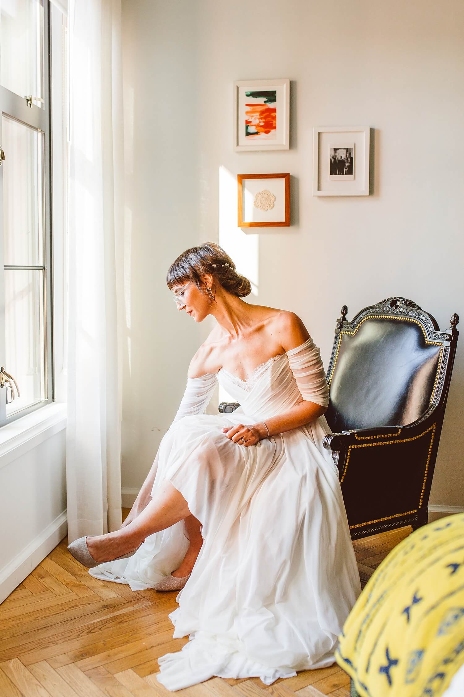 Bride sitting in chair and putting on shoes while getting ready for wedding at The LINE DC | Brooke Michelle Photography