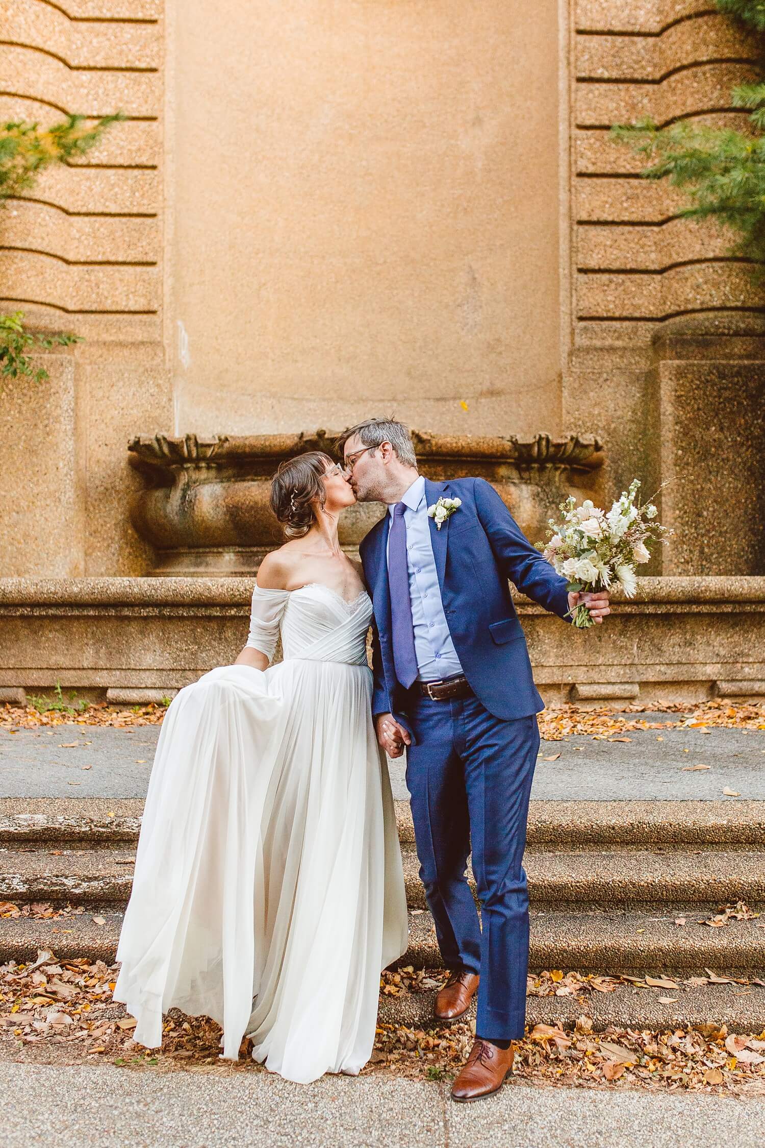 Bride and groom kissing while groom holds bouquet | Brooke Michelle Photography