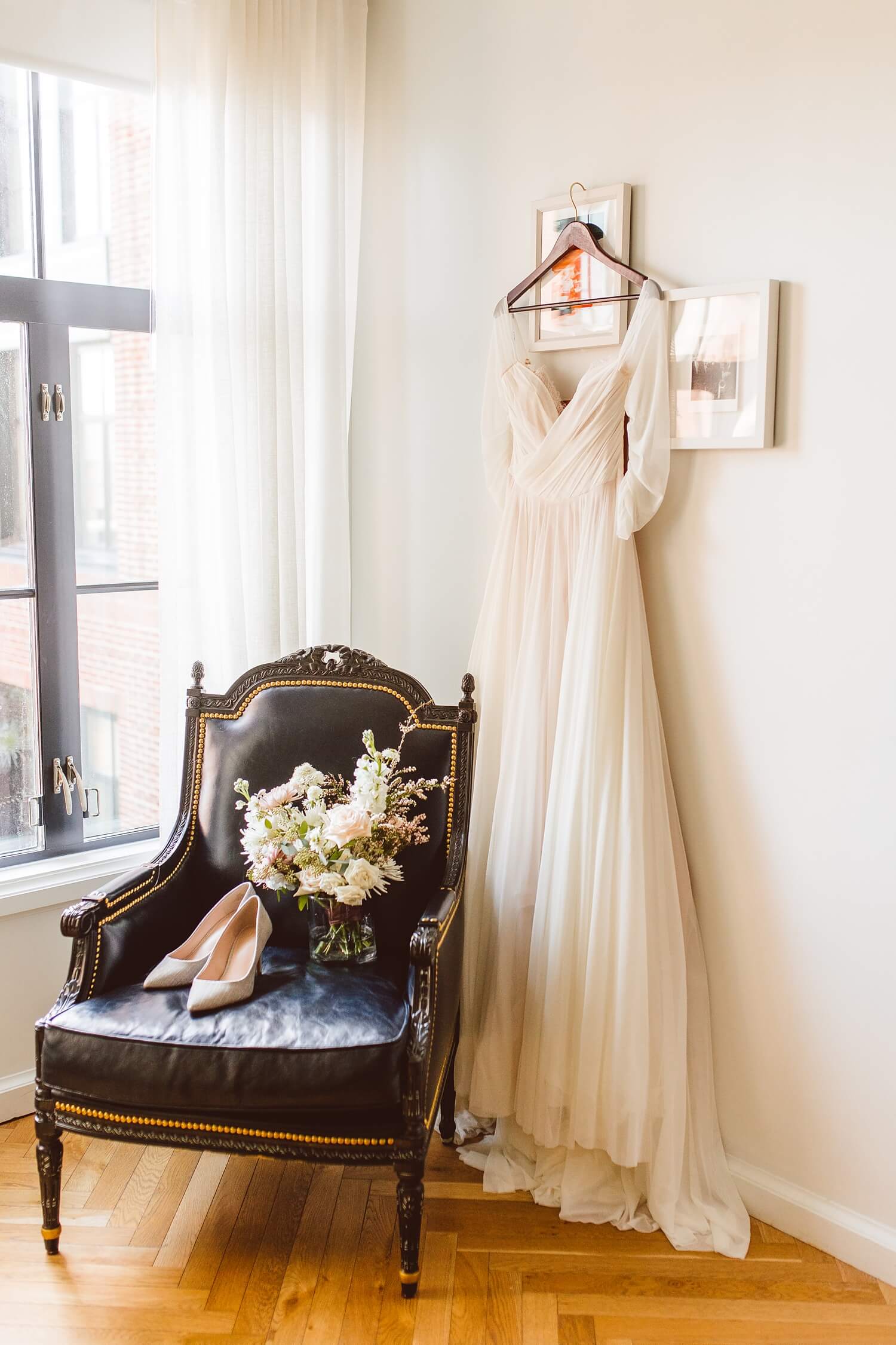Chiffon wedding dress hanging behind chair with bouquet and shoes | Brooke Michelle Photography
