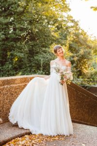 Bride holding up chiffon wedding dress while holding bouquet | Brooke Michelle Photography