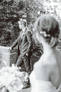 Groom standing near stairs while bride looks at him from a distance | Brooke Michelle Photography