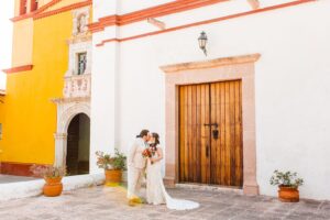 Bride and groom kissing in front of stucco building | Brooke Michelle Photo