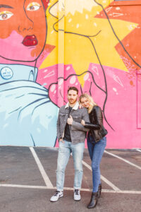Couple posing in front of I Have Seen The Future mural by Mike Worth at118 E. Kingston Avenue - Best Murals in Charlotte for photos