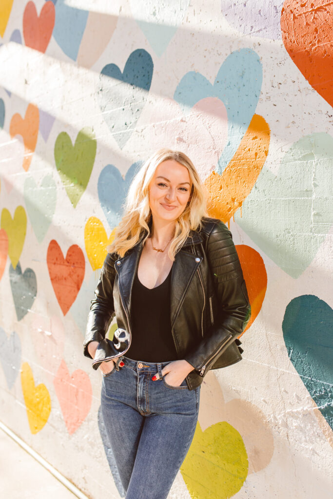 Charlotte Influencer Dre posing by Confetti Hearts mural by Evelyn Henson on West Worthington Ave in Charlotte - Best Murals in Charlotte for photos