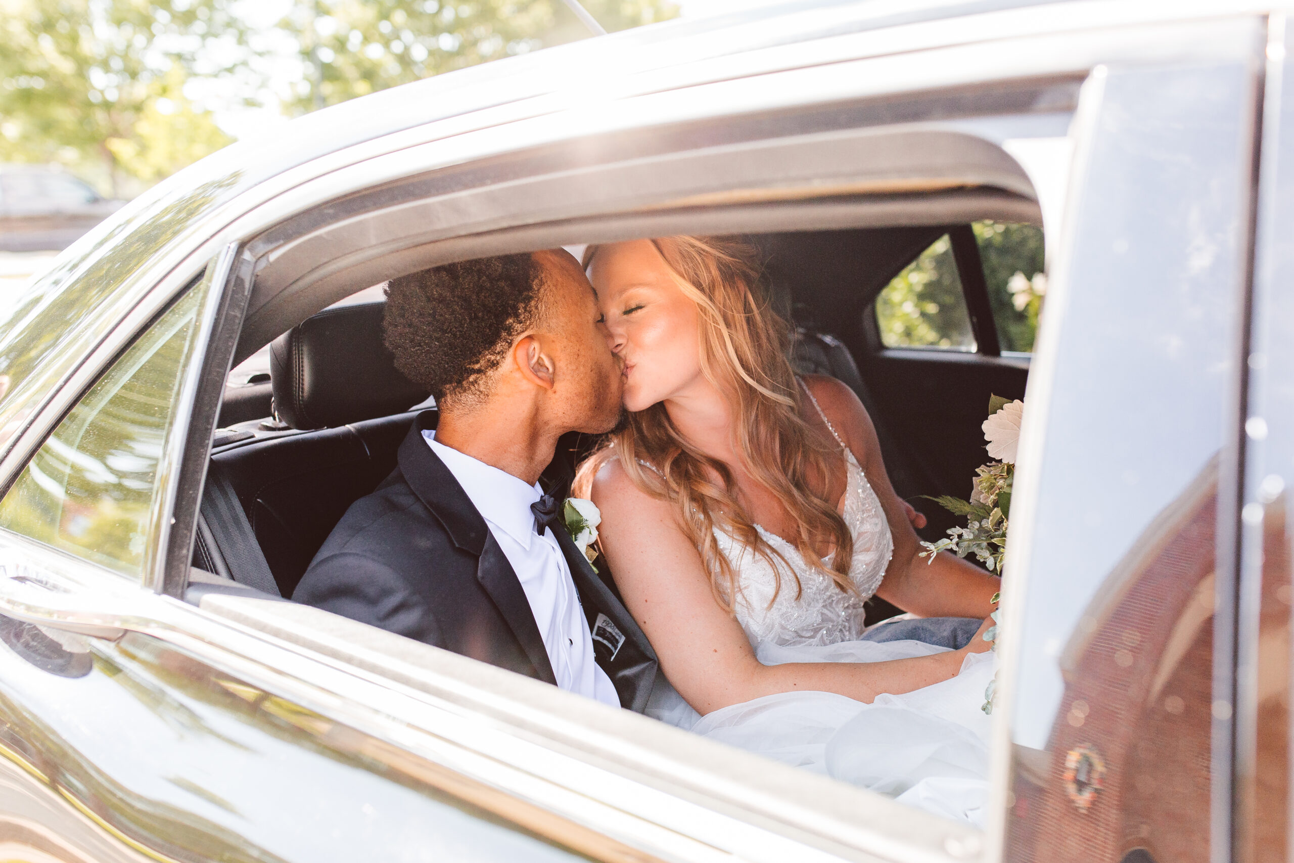 Bride and groom kissing in limo