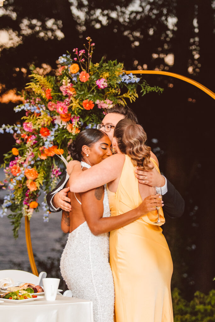 bride and groom hugging the maid of honor