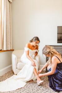 bridesmaid helping her put on her shoes