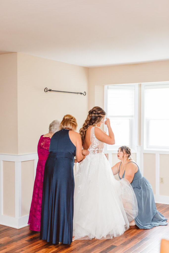grandma and mother of the bride helping her get ready for her elegant bayside wedding ceremony