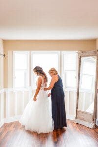 mother of the bride helping her with her wedding dress