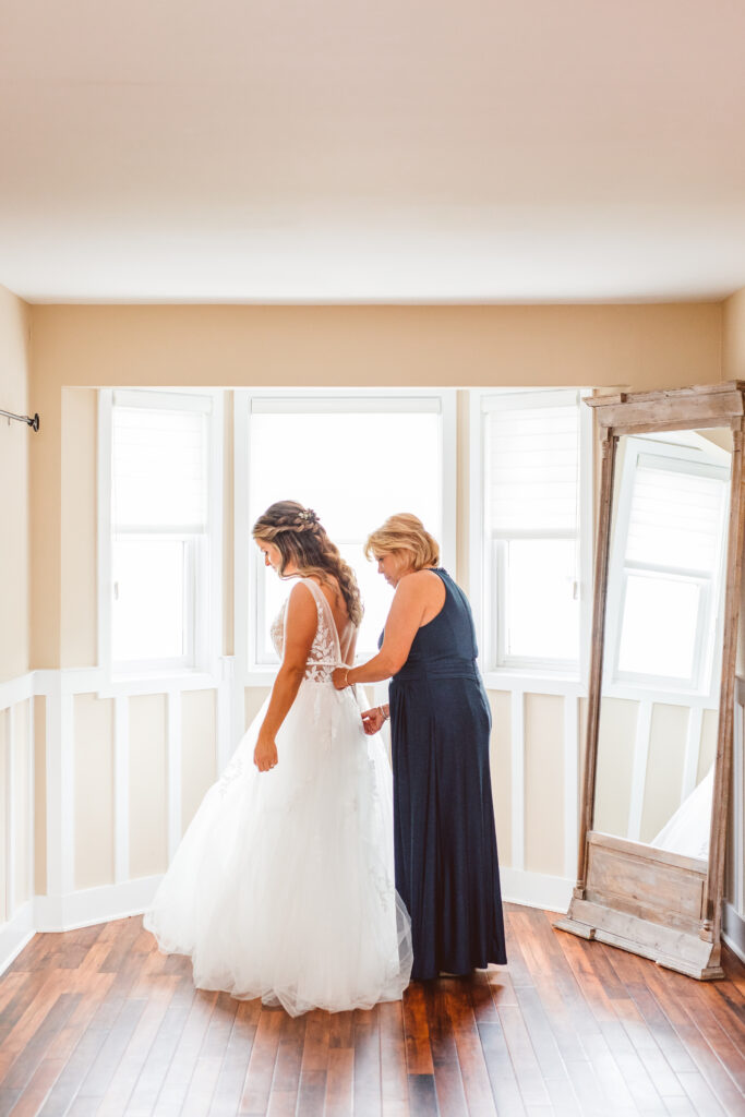 mother of the bride helping her with her wedding dress