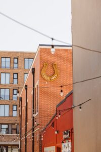 Good Luck horseshoe neon sign glowing on a brick building at Bentonville's 8th Street Market, a unique engagement photo location