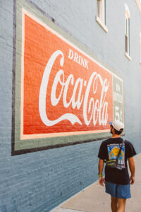 Vintage Coca-Cola mural on a brick building in downtown Bentonville, Arkansas, a colorful engagement photo backdrop