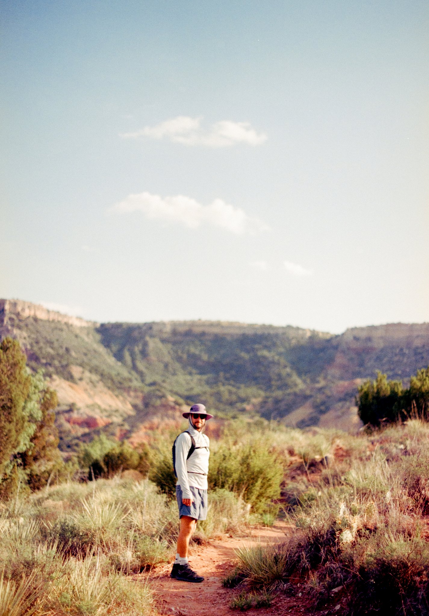 Groom hiking a red dirt trail in Palo Duro Canyon during a Texas adventure elopement near Amarillo