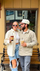 Couple smiling together holding iced coffees outside Cowboy Coffee Co. in downtown Jackson Hole, Wyoming