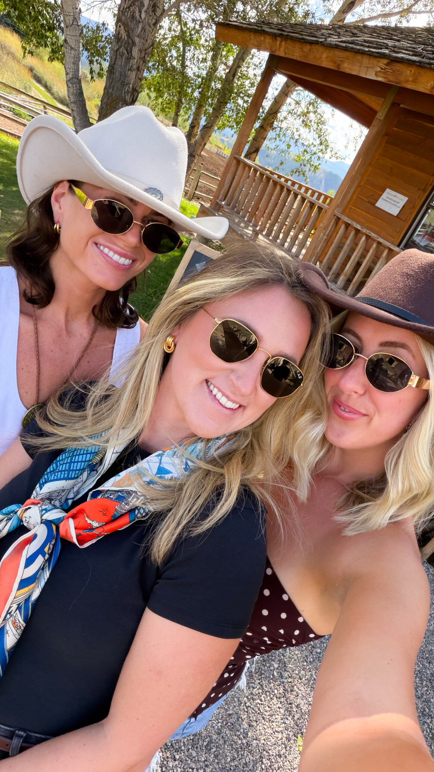 Three friends in cowboy hats and sunglasses smiling for a selfie at Spring Creek Ranch, a popular Jackson Hole girls' trip destination